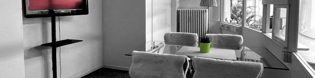 Moderne Wohnzimmer-Ecke mit TV, Sofa und großer Fensterfront.
