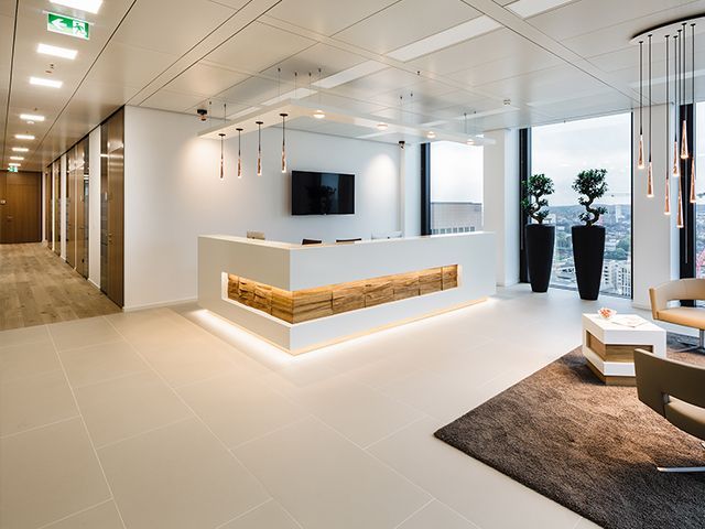 Moderne Lobby mit Empfangstheke, TV, Pflanzen und gemütlicher Sitzgruppe.