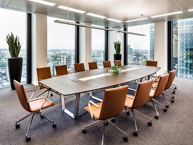 Moderner Konferenztisch mit acht Stühlen und Blick auf Stadtpanorama.