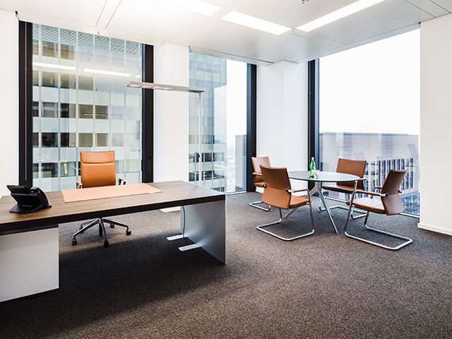 Moderne Bürokonferenzlounge mit Glasfront, Holzkonferenztisch und Lederstühlen.