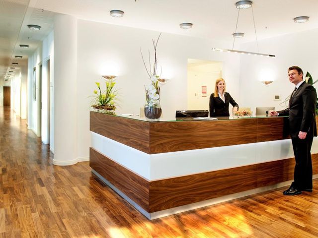 Moderne Hotelrezeption mit freundlichem Personal und Holztheke, gepflegte Atmosphäre.