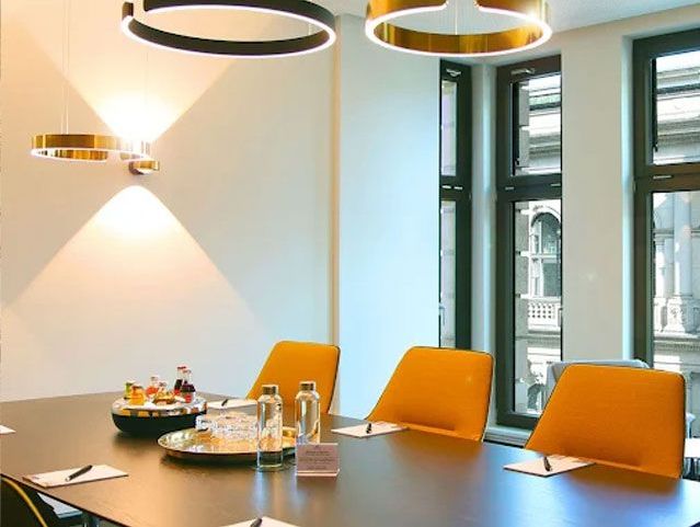 Moderner Besprechungstisch mit orangefarbenen Stühlen und Snacks bei Tageslicht.