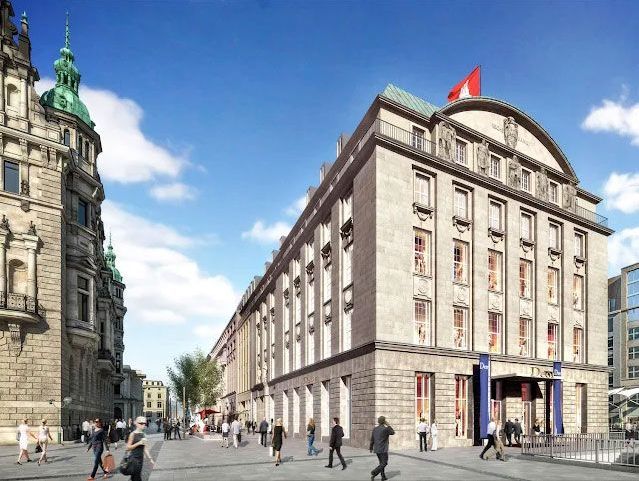 Historisches Gebäudeensemble mit Flagge, belebte Straße und klassischer Architektur.