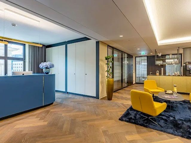 Moderne Empfangshalle mit Holzfußboden, gelben Sitzgelegenheiten und hellen Akzenten.